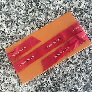 Louis Vuitton red bibbin with gold logo.